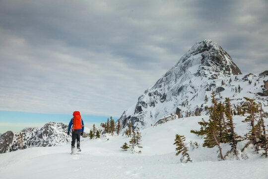 Backpacker on snowshoes approaches a mountain summit