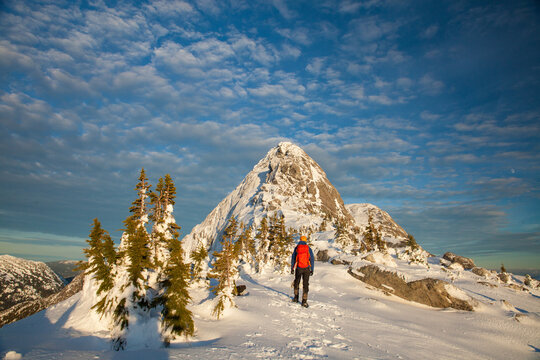 Backpacker approaches snow-covered  mountain peak