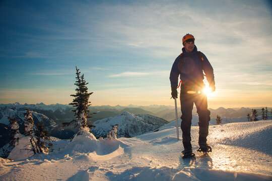 mountain climber hiking using snowshoes at sunset