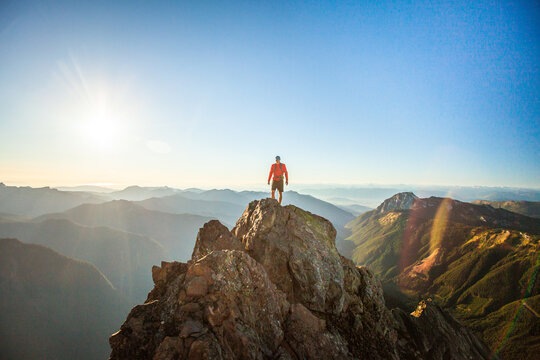 Successful hiker stands on top of rocky mountain summit