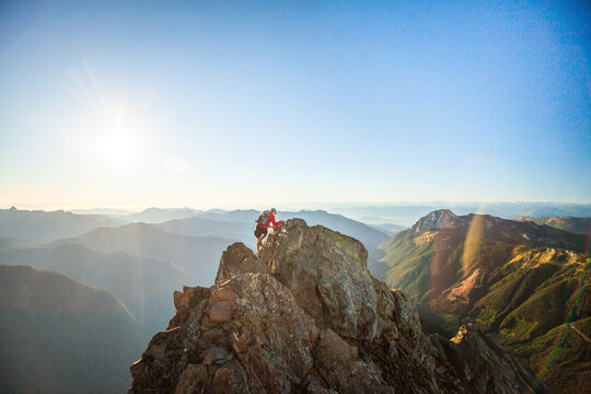 Mountain climber wearing backpack nears summit of rock peak - Powered by Adobe