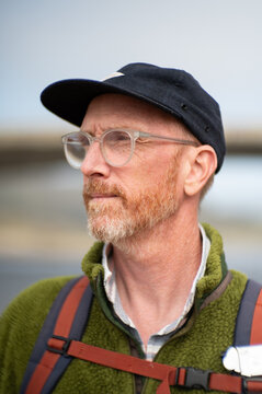 Bearded forty year old with glasses and cap looking off frame