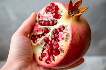Foto op Canvas hand holding a pomegranate open with seeds exposed © altitudevisual
