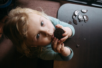 Child eating cream icing out of chocolate cookies
