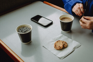 Coffee break at table with paper cups and cookies on napkin