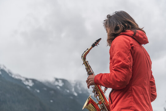 Woman playing saxophone in the mountains with music sheets