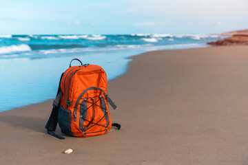 Orange rucksack on the seaside against the sea in fantastic weather. Travel insurance concept....