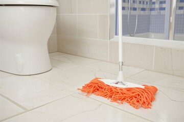 holding mop while cleaning bathroom floor
