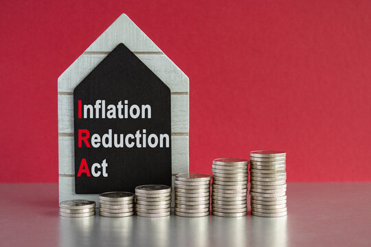IRA inflation reduction act symbol. Concept words inflation reduction act on a black board. Silver coins arranged in a graph in front. Beautiful red background. 