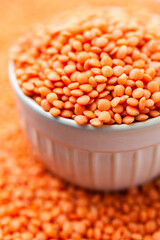 Uncooked red lentils in bowl. Dry orange lentil grains