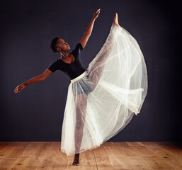 Ballet, black woman and ballerina in studio for dance routine, training and performance. Contemporary, dancing and young female person for elegant art, movement and practice with dark background © peopleimages.com