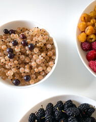 Three bowls with assorted berries, including boysenberry, display on table