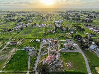 Aerial view of a sunrise over beautiful green scenery with houses and trees in Madera, California. © Wirestock