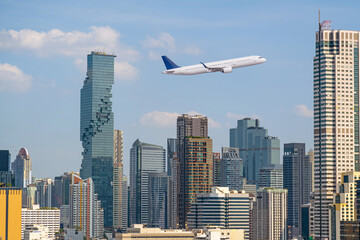 Flying passenger plane in the sky above the city and skyscrapers of the metropolis. The concept of...