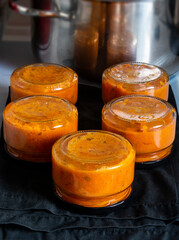 Four jars of citrusinfused sauce displayed on a table for recipes and dishes