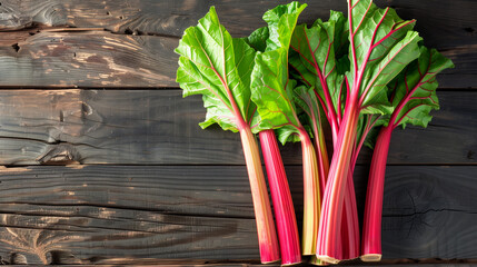 Freshly harvested rhubarb stalks arranged neatly on a rustic wooden table, creating a background with empty space for text about the rhubarb cultivation process 