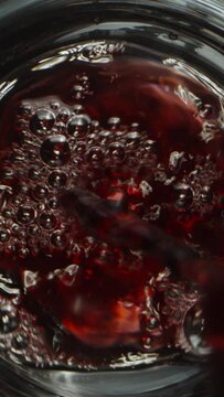 Vertical video.  The camera slides up as I pour wine into a glass through grapes. Dolly slider extreme close-up. 