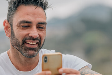 portrait of attractive man with beard outdoors looking at mobile phone