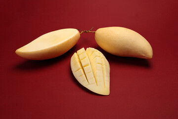 Yellow mango tropical fruit whole sliced cube diced half on red background