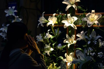 individual praying before a cross adorned with easter lilies © Alfazet Chronicles