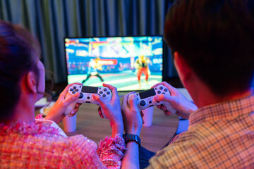 Couple gamer with controlled joystick playing fighting competition video game together on tv screen...