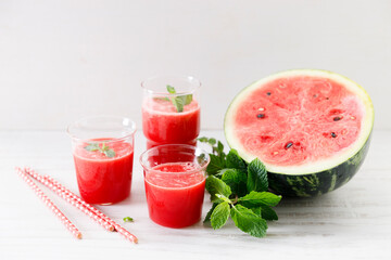 Glass of fresh watermelon smoothie covered with mint leaves.