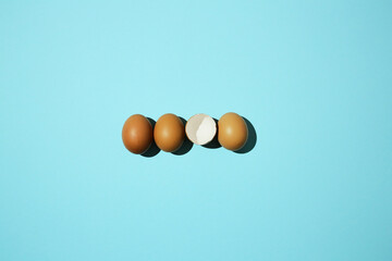 3 organic eggs and one cracked on a blue background,
hatched chick, cracked eggshell, easter concept