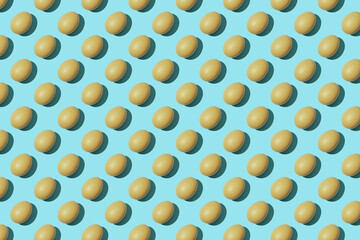 Pattern of raw chicken eggs on a blue background. Top view, easter concept