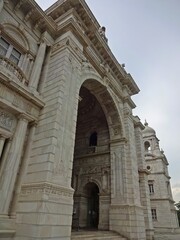 Obraz premium The grand Victoria Memorial Hall stands under a dramatic cloud-filled sky, showing off its exquisite colonial architecture with its towering domes and intricate stonework.