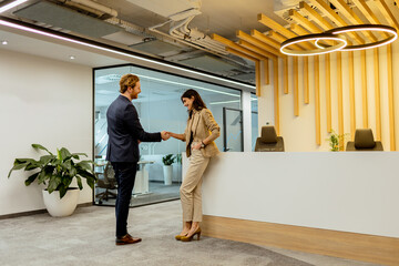 Warm Handshake Between Colleagues In Modern Office Lobby Under Ambient Lighting - 768597698
