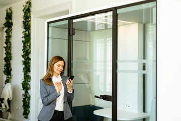 Elegant businesswoman checking her smart watch in a modern office environment - 768598493