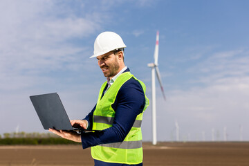 Engineer in High-Visibility Vest Analyzing Data on Laptop at Wind Farm During Daytime. Generative AI - 768599084