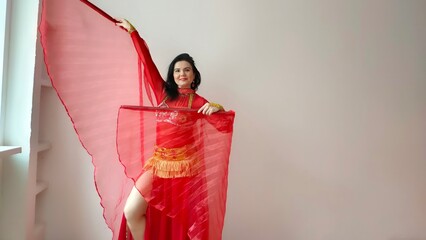 A dancer in a red suit is dancing with a red wings an oriental dance on a white background. Free...
