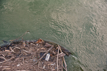 A lot of tree branches and garbage on the river water. Environmental problem concept