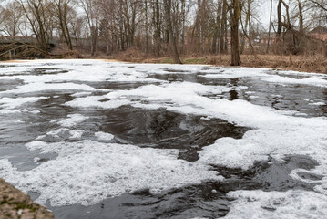 Foaming unclean water in a small river. Concept of pollution and water contamination, spring or autumn nature view on the background