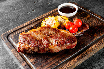 grilled steak paired with roasted tomatoes, corn, and barbecue sauce on a rustic wooden board. The...