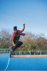 Front view of a young latin skater doing freestyle and doing tricks with inline skates in an...