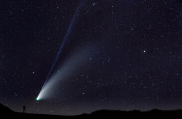 Cometa che passa vicina all'orizzonte, di notte, con un fotografo che esegue una fotografia - 768613075
