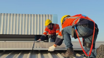 electric engineers survey and inspect solar panels installation on the factory metal sheet roof top.