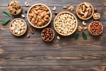 mixed nuts in wooden bowl. Mix of various nuts on colored background. pistachios, cashews, walnuts,...