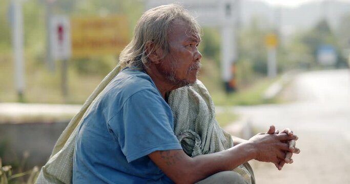 An Asian man who is a poor ragpicker or collects garbage and sells, sitting on the side of the road in the morning