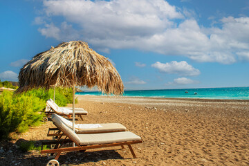beautiful pebble beach and emerald water. sun lounger and straw umbrella on a deserted beach. Mediterranean coast.
