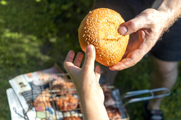 Father gives his son bread. Sesame bun. Close-up of hands. Quotes from Holy Scriptures. Summer...