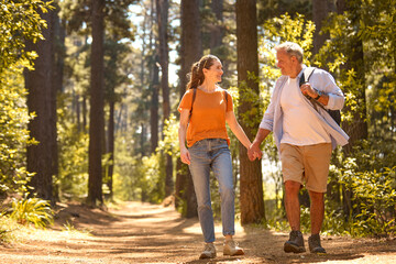 Senior Retired Couple Holding Hands Hiking Along Trail In Countryside