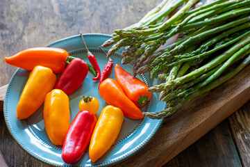 asparagus and bright colored peppers on a blue plate and on a wooden board.