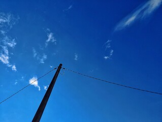 Electric pole and wires under blue sky 