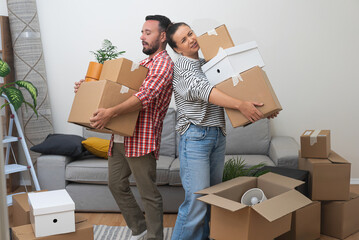 Overstressed couple of man and woman hold heavy boxes with goods delivered to new apartment cardboard packages stacked on floor in living room of accommodation - obrazy, fototapety, plakaty