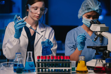 Life scientists researching in laboratory. Focused female life science professional pipetting...