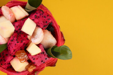 Beautiful Mangosteen mango dragon fruit cube fruit salad in dragon fruit skin bowl on yellow background green banana leaf