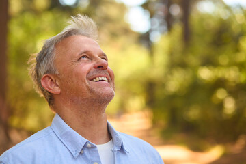 Peaceful Senior Man Relaxing Standing Amongst Nature In Forest Surrounded By Trees